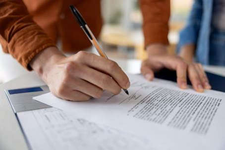 Close-up on a man signing a deed while buying a house - home ownership